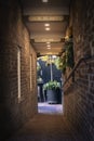 Dark narrow brick alleyway leading up into a restaurant