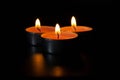 Dark night background, composition of three candles. Black table, side view. Candles Burning at Night. Orange taper burning in Royalty Free Stock Photo