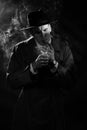 Dark noir portrait of a male detective lighting a cigarette. Private detective, spy, investigation concept. Royalty Free Stock Photo