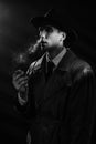 Dark noir portrait of a male detective smoking a cigarette. Private detective, spy, investigation concept.