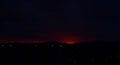 Dark Obscurity: Somber Sunset\'s Red Glow Over Black Mountains, Hills Touching the Horizon