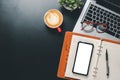 Dark Office desk with laptop computer, Blank screen smart phone, cup of coffee, pen and notebook, copy space, Mock up Royalty Free Stock Photo