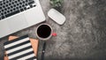 Dark office desk workplace with laptop, notebook, mouse, pen and cup of coffee Royalty Free Stock Photo
