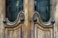 Dark old brown doors with bronze handles and glass. Wooden door with windows with street reflection, closeup Royalty Free Stock Photo