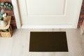 Dark olive door mat on wooden floor in hall, above view Royalty Free Stock Photo