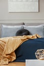Dark and orange blankets on comfortable double bed in grey stylish bedroom