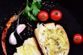 In a dark pan are two slices of white bread and olive oil, surrounded by peppers, tomatoes, garlic and parsley with oregano Royalty Free Stock Photo