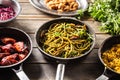 Dark pans with various food such as spaghetti pesto, risotto, and glazed chicken wings Royalty Free Stock Photo