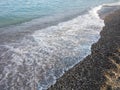 Dark pebbles beach and blue sea wave