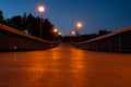 Dark pedestrian bridge lit up by street lights over rowing canal in Plovdiv, Bulgaria