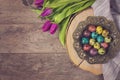 Dark photo of Easter quail eggs in an ancient metal bowl. Beautiful spring flowers - purple tulips on a wooden background. Floral Royalty Free Stock Photo