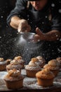 Dark photo of muffins. Above them a man\'s hand is holding a small silver sieve and sprinkles with powdered sugar Royalty Free Stock Photo