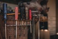 Dark photo of screw drivers hanging on the tool panel in old shed on sunset. Close up photo of colorful working tools on the wall