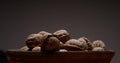 dark photo. walnuts on brown clay plate against dark background.