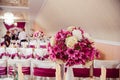 Dark pink bouquet stands in white vase on the rich dinner table Royalty Free Stock Photo