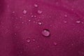 Dark pink waterproof fabric with water drops as background, closeup Royalty Free Stock Photo