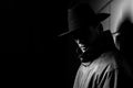 Dark portrait of a man in a raincoat with a hat at night on the street