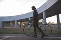 Dark portrait of a rider. Silhouette of a cyclist with a bicycle on the background of a bridge