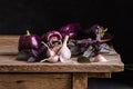 Dark purple peppers with leaves of basil and garlic on old rustic wooden table Royalty Free Stock Photo