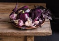 Dark purple peppers with leaves of basil and garlic on old rustic wooden table Royalty Free Stock Photo