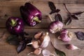 Dark purple peppers with leaves of basil and garlic on old rustic wooden table on black background Royalty Free Stock Photo