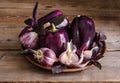 Dark purple peppers with leaves of basil and garlic on old rustic wooden table Royalty Free Stock Photo