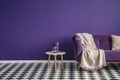 Dark purple sofa with a blanket beside a small table with bottle