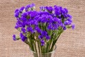 Dark Purple Statice Limonium sinuatum Flowers in clear glass vase on natural burlap. Mediterranean plant in Plumbagin