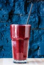 Dark red or Burgundy fruit and berry smoothie in a large glass against a dark stone wall Royalty Free Stock Photo