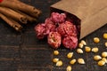 A Bag of Dark Red Cinnamon Popcorn on a Wooden Kitchen Table Royalty Free Stock Photo