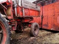 Dark red grunge background with part of old neglected tractor with rubber dirty wheels