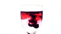 Dark red ink dropping in glass of water Royalty Free Stock Photo