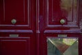 Dark red painted wooden door with vintage brass doorknobs and geometric plate. Shabby surface of antique door. Framed wood texture