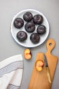 Dark red purple whole and halved plums with bright yellow reddish flesh on white enamel plate. Wooden cutting board cotton towel