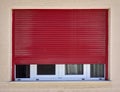 Dark red rolling shutters and white frame window on beige wall, Royalty Free Stock Photo