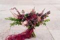 Dark red wedding bouquet stands on stone wall background Royalty Free Stock Photo