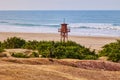 Dark red wooden lifeguard tower and empty sandy beach on the seashore in the off season Royalty Free Stock Photo