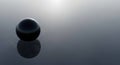 Dark reflective sphere rests on a ripple surface Royalty Free Stock Photo