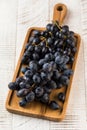 Dark ripe grapes on a board on a light wooden background. Fruit