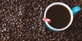 Dark roasted coffee beans background with blue filled coffee cup with peppermint