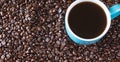 Whole coffee beans background with blue filled coffee cup Royalty Free Stock Photo