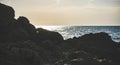 Dark rocks and stones on the Black Sea coast against which blue tidal waves beat in the backlight Royalty Free Stock Photo