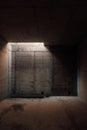 a dark room with concrete walls and a small light opening in the ceiling