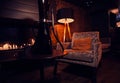 Dark room with working fire place, velvet armchair, lamp and black hookah