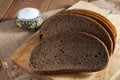 Dark rye bread on wooden cutting board and salt in saltshaker on burlap