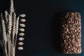 Dark rye, cereal bread with sunflower seeds, whole bread, wheat stems, pumpkin seeds on a dark background shale board, concept of Royalty Free Stock Photo