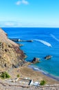 Dark sandy Prainha Beach by the Atlantic Ocean in Madeira, Portugal. Surrounded by volcanic rocks and cliffs. People on the beach Royalty Free Stock Photo