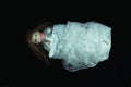 A dark, scary edit of an old doll wrapped in a white net curtain on a black background