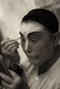 Dark sepia version of an elderly Chinese Teochew opera singer doing her own makeup Royalty Free Stock Photo