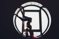 The dark silhouette of a beautiful woman with child on the background of the round window. yoga, acrobatics. Royalty Free Stock Photo